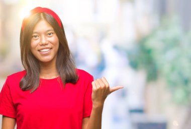 Genç Asyalı kadın arıyorum ve başparmak yanında yukarıyı mutlu yüz ile gülümseyen izole arka plan üzerinde.