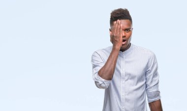 El yüz ve sürpriz duygu kendinden emin gülümseme ile tek gözüyle kapsayan izole arka plan üzerinde genç Afro-Amerikan adam.