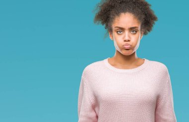 Komik surat ile yanakları şişirme izole arka plan üzerinde kış kazak giyen genç afro Amerikalı kadın. Ağız ile hava, deli ifade şişirilmiş.