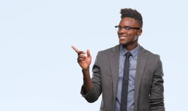 Kameraya bakarak yan el ve parmak ile işaret eden genç Afro-Amerikalı iş adamı yüzünde kocaman bir gülümseme ile izole arka plan üzerinde.