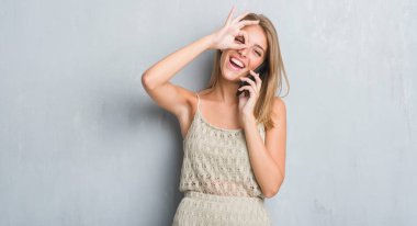 Mutlu yüz el parmaklarının arasından seyir göz üzerinde ok işaretiyle yapıyor gülümseyen ile konuşan grunge gri duvar güzel genç kadın