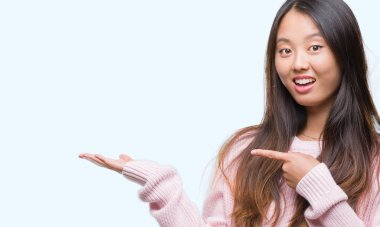 Genç Asyalı kadın üzerinden hayran ve el ile sunulması ve parmak ile işaret ederken kameraya gülümseyen izole arka plan.