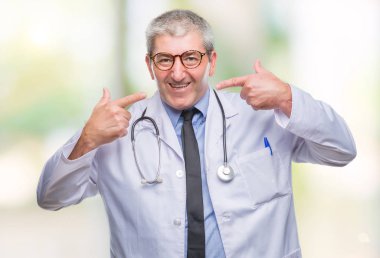 Yakışıklı kıdemli Doktor adam kendinden emin gösterilen ve işaret parmakları diş ve ağız ile gülümseyen izole arka plan üzerinde. Sağlık kavramı.