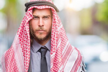 Genç yakışıklı Arap adam uzun saçlı keffiyeh izole arka plan şüpheci ve sinir, papatyanın üzgün üzerinde sorunu nedeniyle giyiyor. Negatif kişi.