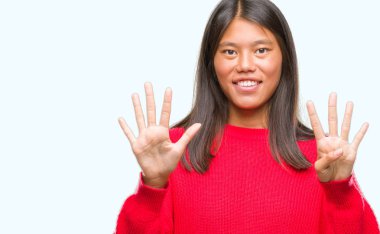 Genç Asyalı kadın giyiyor kış kazak gösterilen ve parmakları ile işaret izole arka plan üzerinde numara 9 kendinden emin ve mutlu gülümseyerek süre.