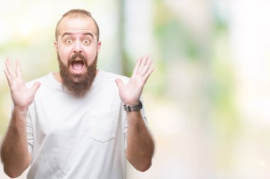 Üzerinde rahat t-shirt giyen genç beyaz hipster adam deli kutluyor arka plan izole ve başarı için kaldırdı kollarını açarak hayrete ve heyecanlı çığlık gözleri açık. Kazanan kavramı