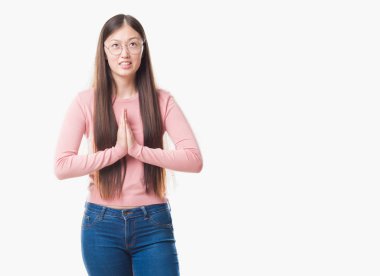 İzole arka plan yalvarıyor ve umut ifade yüzünde çok duygusal ve endişe ile birlikte elleriyle dua gözlüklü Genç Çinli kadın. Bağışlanmak. Din kavramı.