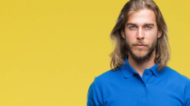 Yüzünde ciddi bir ifade ile izole arka plan üzerinde uzun saçlı Genç yakışıklı adam. Basit ve doğal kameraya bakıyor.