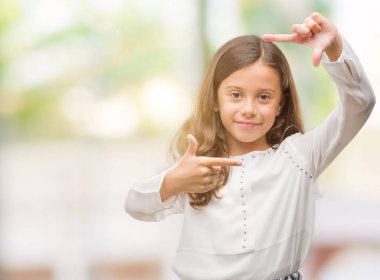 Elle yapma çerçeve ve parmakları ile mutlu yüz gülen esmer İspanyol kız. Yaratıcılık ve Fotoğrafçılık kavramı.