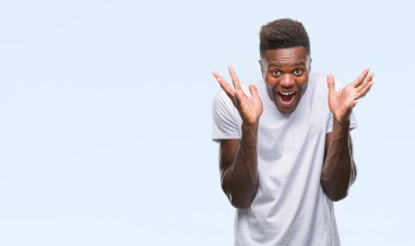 Afrikalı-Amerikalı genç deli kutluyor ve silah ile başarı için heyecanlı çığlık kaldırdı ve açık gözleri hayret izole arka plan üzerinde. Kazanan kavramı