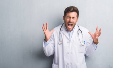 Yakışıklı genç doktor adam kızgın ve silah ile başarı için deli duvar gri grunge kutluyor üzerinden kaldırdı ve heyecanlı çığlık gözler kapalı. Kazanan kavramı