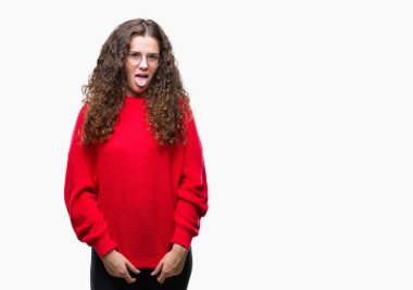 Güzel esmer kıvırcık saçlı Genç kız gözlük ve kış kazak dilini izole arka plan üzerinde mutlu komik ifade ile dışarı. Duygu kavramı.