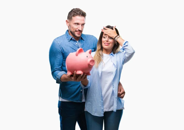 Young couple in love holding piggy bank over isolated background stressed with hand on head, shocked with shame and surprise face, angry and frustrated. Fear and upset for mistake.
