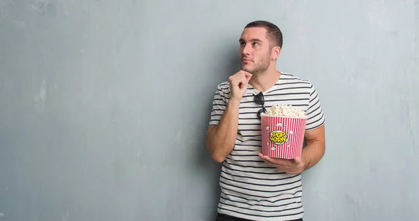 Kaukasische Jongeman Grijs Grunge Muur Eten Popcorn Ernstige Gezicht Denken — Stockfoto