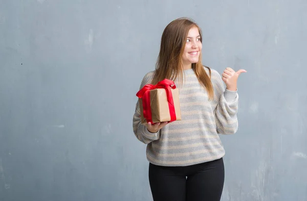 Young Adult Woman Grey Grunge Wall Holding Present Pointing Showing — Stock Photo, Image