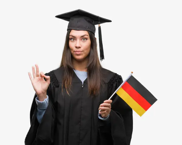 Mujer Hispana Joven Vistiendo Uniforme Graduado Sosteniendo Bandera Alemania Haciendo —  Fotos de Stock