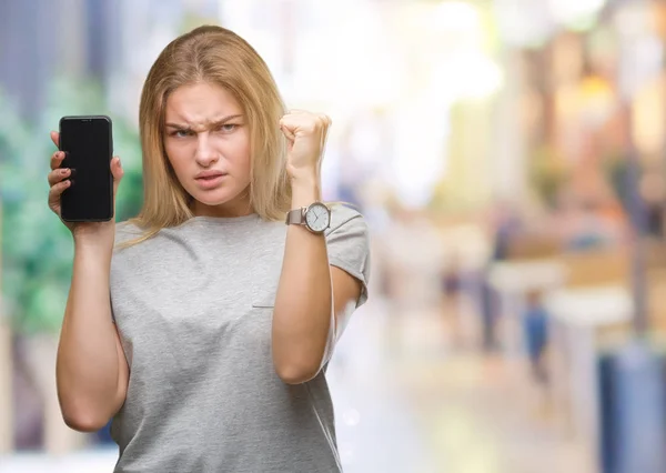 年轻的白种人妇女显示屏幕的智能手机在孤立的背景恼火和沮丧的叫喊与愤怒 疯狂和大喊大叫的举手 愤怒的概念 — 图库照片