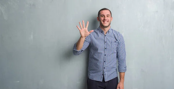 Joven Caucásico Hombre Sobre Gris Grunge Pared Mostrando Apuntando Hacia —  Fotos de Stock