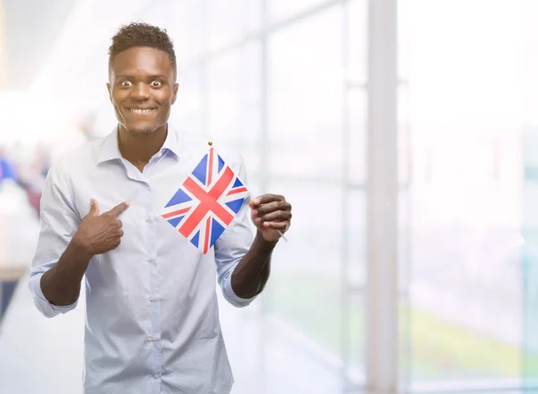 Mladý Americký Muž Drží Velká Británie Vlajka Překvapením Tvář Ukazováčkem — Stock fotografie