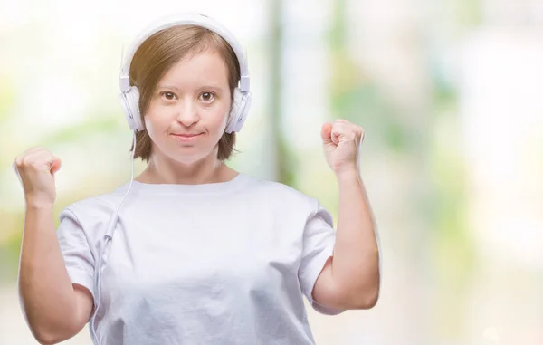 唐氏综合征的年轻成年妇女戴着耳机在与世隔绝的背景下非常高兴和兴奋做赢家手势与手臂举起 微笑和尖叫的成功 庆祝概念 — 图库照片