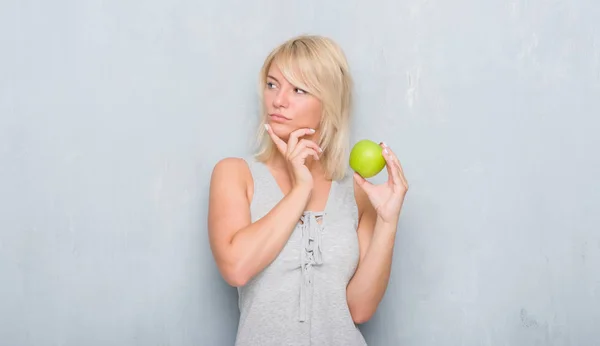 Volwassen Kaukasische Vrouw Grunge Grijs Muur Eten Groene Appel Ernstige — Stockfoto