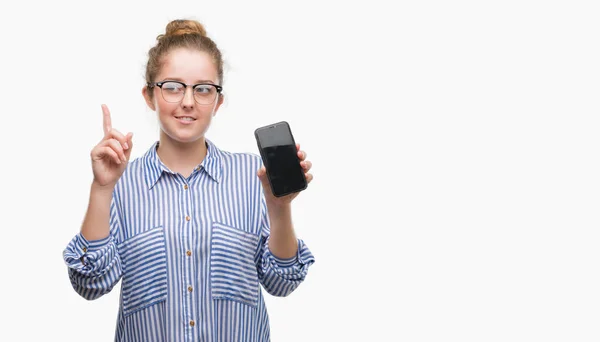 年轻的金发女人使用智能手机惊讶于一个想法或问题指向手指与快乐的脸 — 图库照片