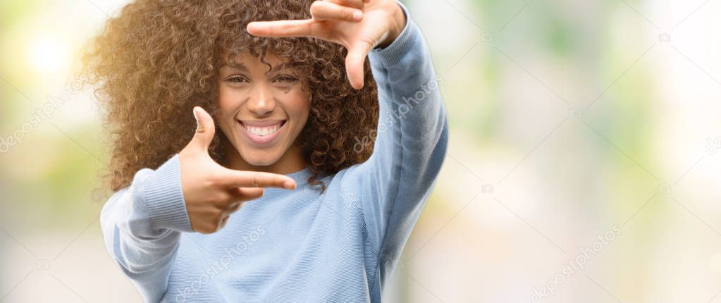 African american woman wearing a sweater smiling making frame with hands and fingers with happy face. Creativity and photography concept.