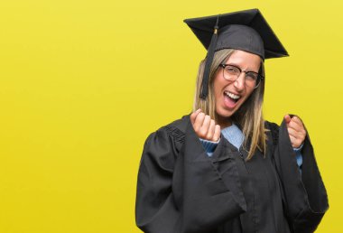 Giyen genç güzel kadın üniforma izole arka plan çok mutlu ve heyecanlı kaldırdı, silah ile kazanan jest yapıyor üzerinde gülümseyen ve başarı için çığlık mezun oldu. Kutlama kavramı.