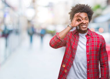 Afro Amerikalı adam gülümsüyor, parmakları ile mutlu yüz üzerinden seyir göz el ile ok jest yapıyor izole arka plan üzerinde.