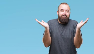 Genç beyaz hipster adam izole arka plan clueless ve şaşkın bir ifadeyle kollar ve eller kaldırdı. Şüphe kavramı.