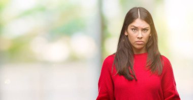 Kırmızı kazaklı şüpheci ve sinir, papatyanın üzgün sorunu nedeniyle giyen genç güzel İspanyol. Negatif kişi.