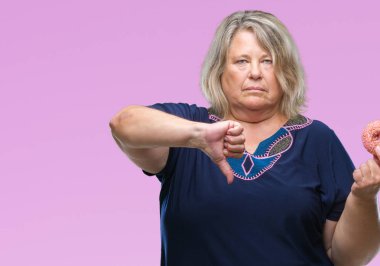 Kızgın yüz, eksi işareti aşağı antipati başparmak ile gösterilen, ret kavramı ile izole arka plan üzerinde şeker donut yemek üst düzey artı boyutu kafkas kadın