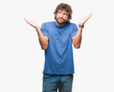Yakışıklı İspanyol modeli adam izole arka plan clueless ve şaşkın bir ifadeyle kollar ve eller kaldırdı. Şüphe kavramı.