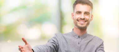 Sarılmak için kollarını açarak gülümseyerek kameraya bakacak genç hipster adam. Neşeli ifade kucaklayan mutluluk.