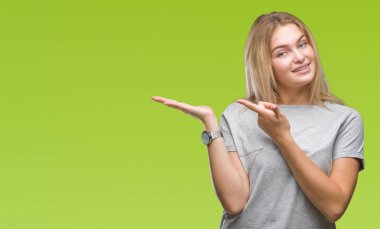 Hayret ve el ile sunulması ve parmak ile işaret ederken kameraya gülümseyen izole arka plan üzerinde beyaz kadın.