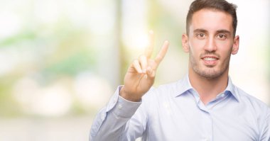 Zafer işareti yapıyor parmak gösterilen kamera seyir gülümseyen yakışıklı genç iş adamı. İki numaralı.