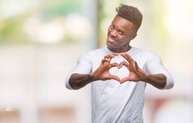 Afrikalı-Amerikalı genç aşık kalp simgesi ve elleriyle şekil gösteren gülümseyen izole arka plan üzerinde. Romantik kavramı.