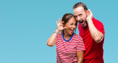 Orta yaş İspanyol çift izole arka plan ile gülümseyen üzerinde aşık bir işitme söylenti ya da dedikodu için dinleme kulak teslim. Sağırlık kavramı.