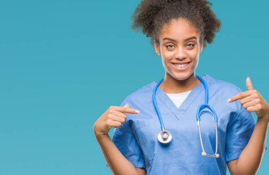 Yüzünde gülümseme ile kendinden emin görünüyorsun, kendini gururlu ve mutlu parmakları ile işaret izole arka plan genç afro Amerikalı doktor kadın.