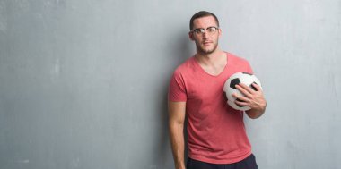 Futbol futbol topu kendine güvenen bir ifade ile acımak yüz ciddi düşünüyorum tutarak gri grunge duvarın üzerinden beyaz delikanlı