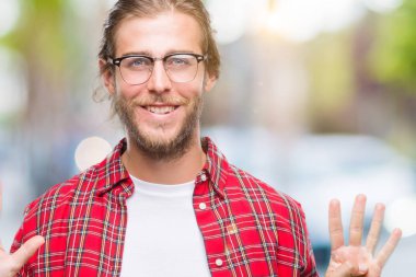 Genç yakışıklı adamla uzun saç gözlük gösterilen ve parmakları ile işaret izole arka plan üzerinde numara 9 kendinden emin ve mutlu gülümseyerek süre.
