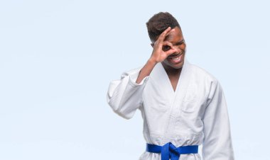 Genç Afro-Amerikan adam gülümsüyor, parmakları ile mutlu yüz üzerinden seyir göz el ile ok jest yapıyor kimono giyen izole arka plan üzerinde.