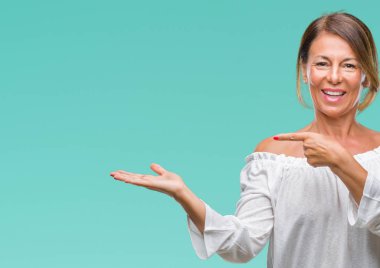 Orta yaş üzerinden hayran ve el ile sunulması ve parmak ile işaret ederken kameraya gülümseyen izole arka plan İspanyol kadın kıdemli.