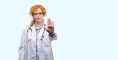 Elin avuç durağı şarkı yapıyor Doktor üniforması giyen genç redhead kadın. Negatif ve ciddi bir jest yüz ifadesiyle uyarı.