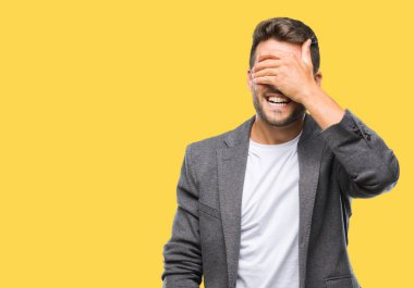 Genç yakışıklı iş adamı gülümsüyor ve gözleri için sürpriz kapsayan yüz el ile gülüyor izole arka plan üzerinde. Kör kavramı.