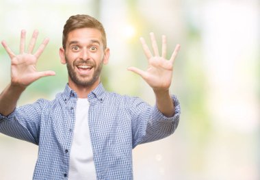 Gösterilen ve parmakları ile işaret izole arka plan üzerinde beyaz t-shirt giyen genç yakışıklı adam kendinden emin ve mutlu gülümseyerek süre on numara.