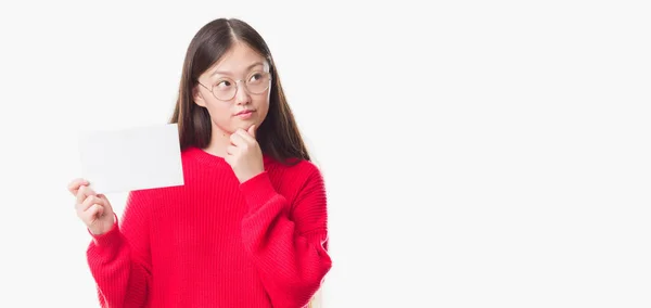 年轻的中国妇女在孤立的背景下持有空白卡严肃的面孔思考问题 非常困惑的想法 — 图库照片
