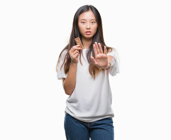 Junge Asiatin Isst Schokoriegel Vor Isoliertem Hintergrund Mit Offener Hand — Stockfoto