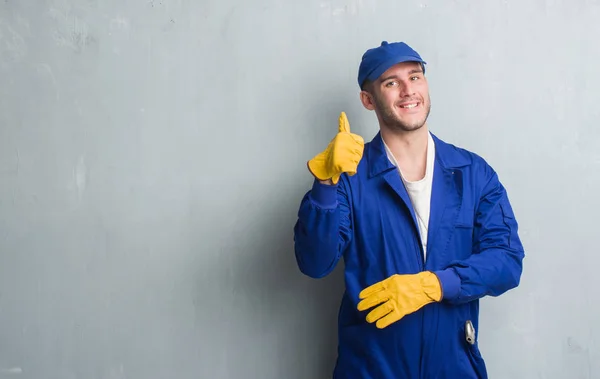 Homem Caucasiano Jovem Sobre Parede Grunge Cinza Vestindo Uniforme Mecânico — Fotografia de Stock