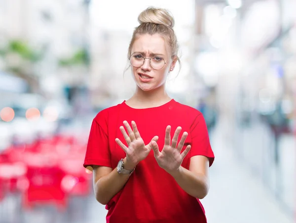 Young blonde woman wearing glasses over isolated background disgusted expression, displeased and fearful doing disgust face because aversion reaction. With hands raised. Annoying concept.